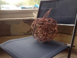 huge, heavy copper-wire apple with brass plug parts inside, arranged like seeds.
